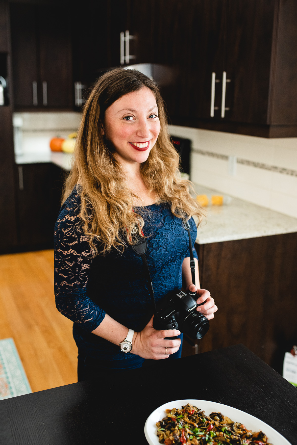 Woman smiling with camera next to food