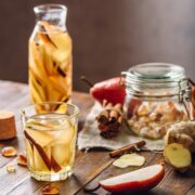 glasses and pitcher with mocktail and cocktail ingredients on wooden background