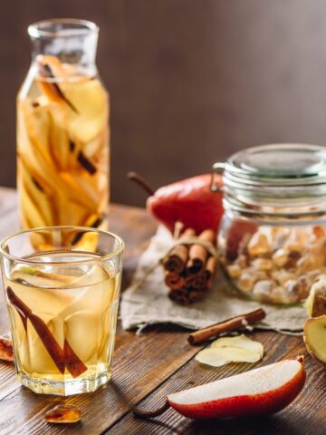 glasses and pitcher with mocktail and cocktail ingredients on wooden background