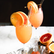 Two glasses with orange slices in them, resembling a non-alcoholic Aperol Spritz mocktail.