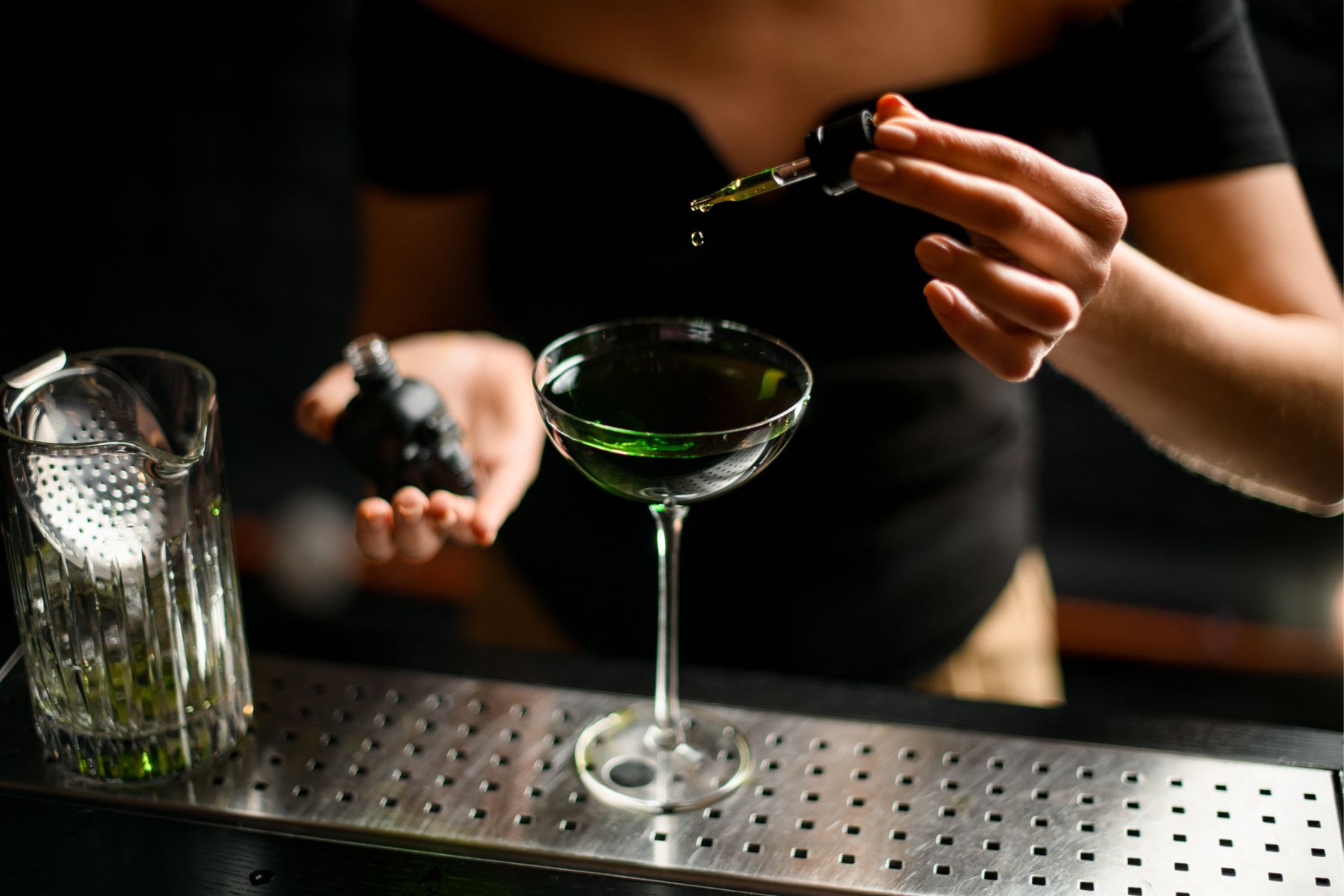 adding bitters to green cocktail