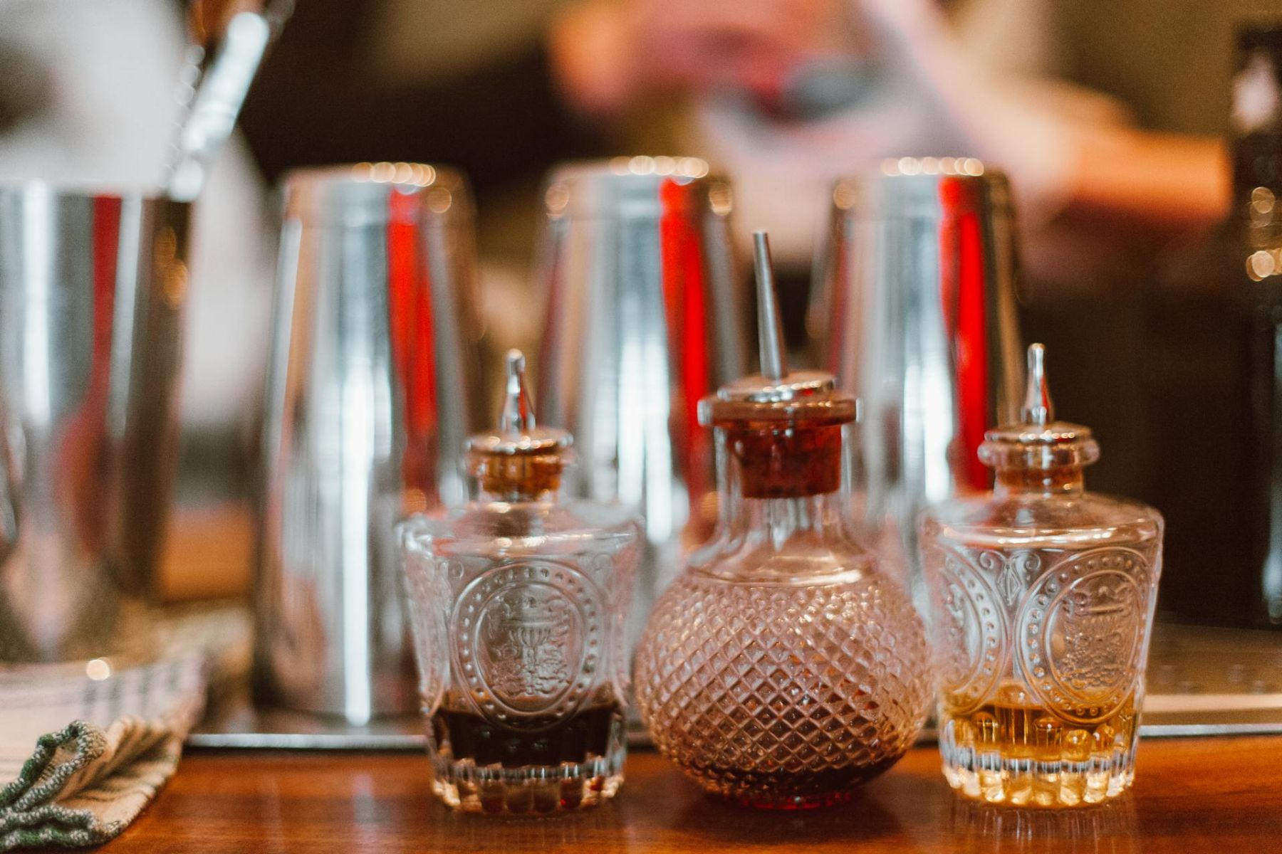 Three craft bitters bottles in a row with shakers in back