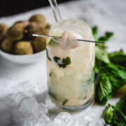 A Virgin Lychee Mojito with mint leaves and ice on a table.